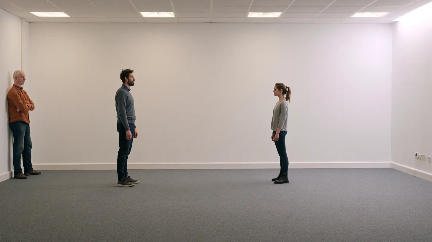 Three people in a bare white room: two facing each other at a distance while a third leans against the wall and watches